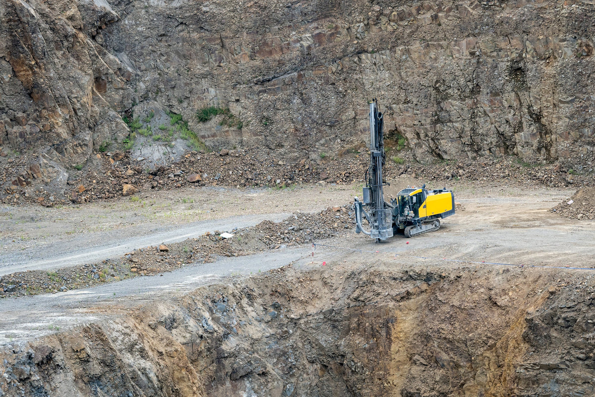 Surface drill rig at the foot of a granite quarry face