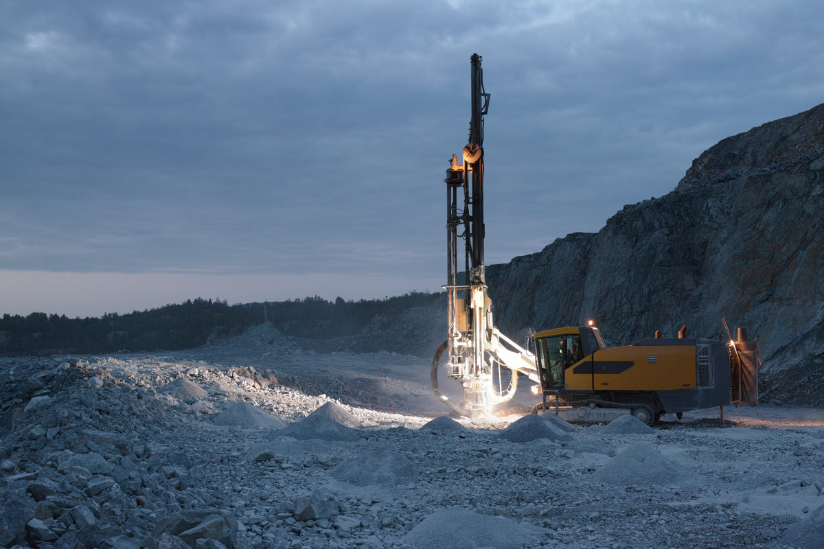 Surface drill rig drilling blast holes in a rock quarry at dusk
